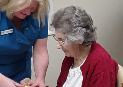 A lady resident at Lulworth House, having help from a staff member to decorate her Easter egg