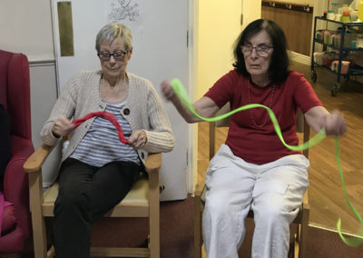 Residents at Lulworth House waving brightly coloured ribbons as part of an active armchair exercise session