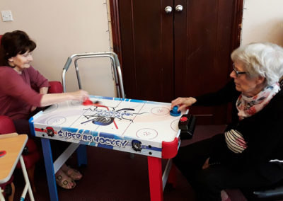 Two lady residents playing air hockey