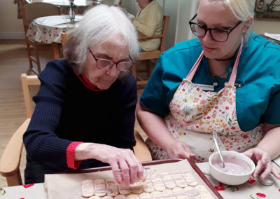 Lady resident and staff member decorating biscuits together