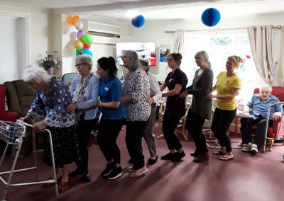 Staff and residents at Lulworth House Residential Care Home dancing in a conga line