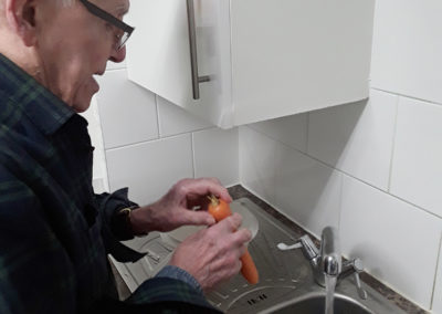 Male resident at a sink, washing vegetables
