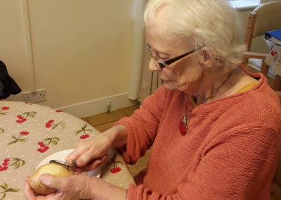Lady resident at a table, peeling potatoes