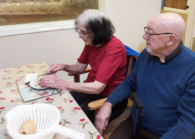 Residents sitting at a table together preparing vegetables for Burns Night