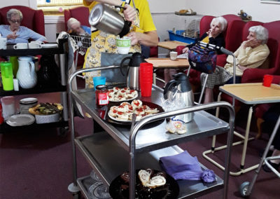 Staff serving drinks and sweets treats from a trolley for Children in Need