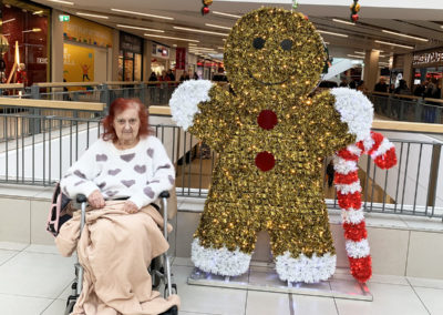 Lady resident in her wheelchair by a glittery gingerbread man decoration in a town centre