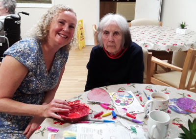 Resident and friend doing paper crafts at a table at Lulworth House