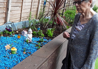 Lady resident looking at the raised bed in the garden at Lulworth House Residential Care Home