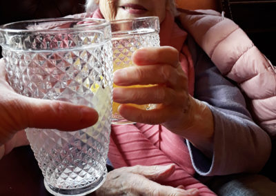 Seated lady resident clicking a glass during a visit to the pub