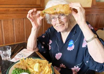 Female residents holding up her fish from her fish and chip dinner at Frankie and Benny's