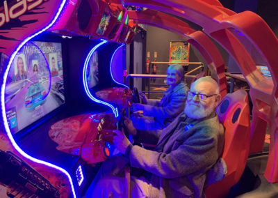 Two Lulworth House residents playing a driving game at the games arcade