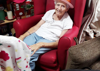 Resident wearing a hat sitting in an arm chair