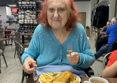 Resident sat at a restaurant table eating a fish and chip lunch