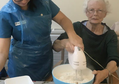 A resident and staff member at Lulworth House mixing cake ingredients