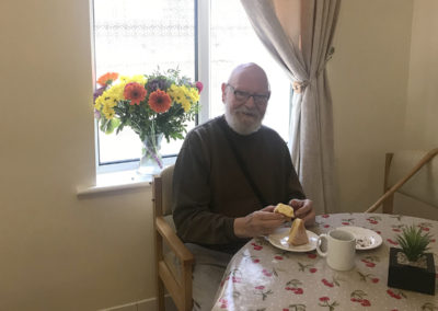 A male resident at Lulworth House enjoying a slice of cake during the Macmillan coffee morning