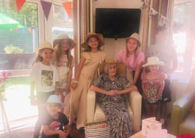 Lady resident surrounded by children, all wearing hats