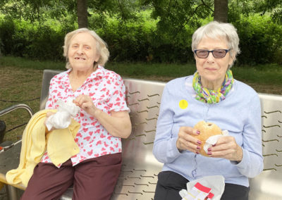 Two lady residents sitting on a park bench eating lunch
