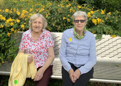 Two lady residents sitting on a park bench together