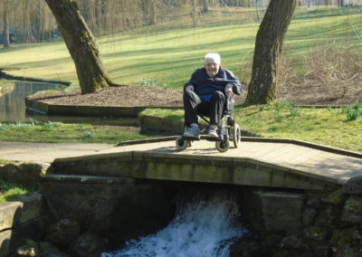 Gentleman in a wheelchair on a small bridge over cascading water