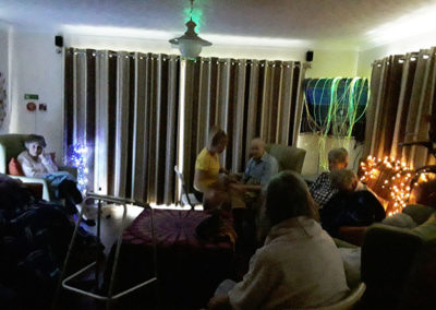Residents in a darkened room enjoying Namaste and sensory lights