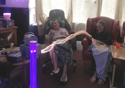 Residents at Lulworth House touch fibre optic strands and look at bubble tubes during a sensory exploration session