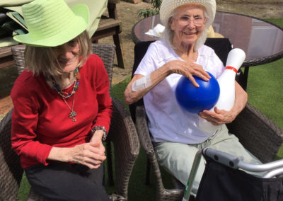 Two Lulworth House residents sitting wearing hats, with skittles in the garden