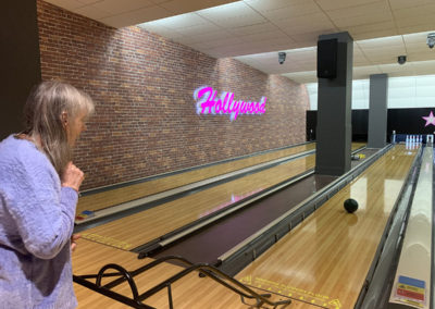 Lady resident using a ball ramp to take a shot at ten pin bowling