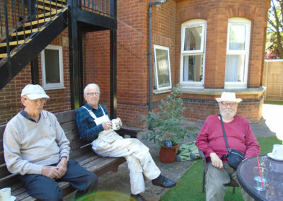 Three gentlemen sitting and relaxing in the garden at Lulworth House Residential Care Home
