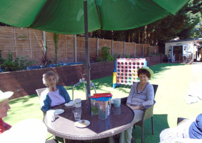 Two ladies sitting and relaxing in the garden at Lulworth House Residential Care Home