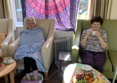 Two lady residents relaxing with a foot massage and a hot drink