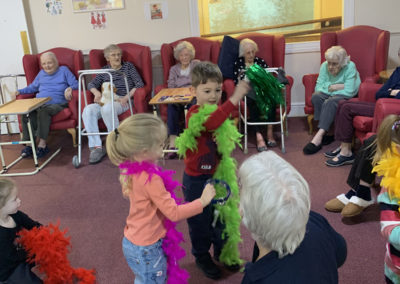Children from Blue Sky Nursery playing with feather boas with Lulworth House residents