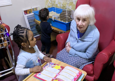 Lady resident enjoying a book with a nursery child on World Book Day