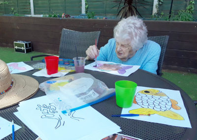 Lulworth House resident painting a fish picture in the garden
