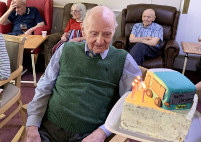 Resident smiling as he receives a camper van birthday cake with candles