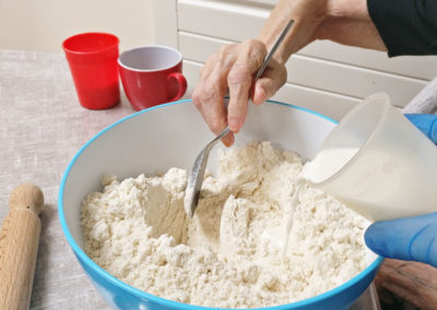 A mixing bowl full of flour and milk, being mixed for scones