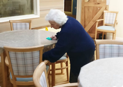 A lady resident helping with cleaning the dining room at Lulworth House