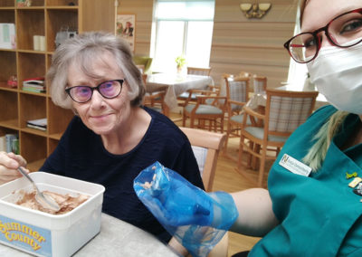 Staff member and resident with a tub of icing and icing bag